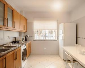 a kitchen with wooden cabinets and a white refrigerator at Harbour's way, spacious and cosy apartment, with AC in Olhão