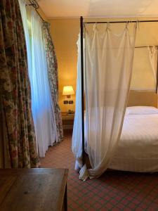 een slaapkamer met een hemelbed en gordijnen bij Locanda Maison Verte in Cantalupa