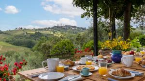 a wooden table with breakfast food and a view of a hill at Villa Caterina 8, Emma Villas in San Gimignano
