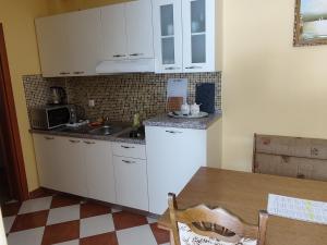 a kitchen with white cabinets and a sink and a table at Apartmani Golomeić in Crikvenica