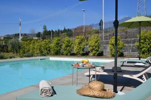 uma piscina com uma mesa, uma cadeira e um guarda-sol em Modern Villa, pool + gym em Giarre