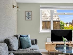 a living room with a couch and a tv at Pass the Keys Flat 1 Elegance Meets Modern Luxury in Whitstable