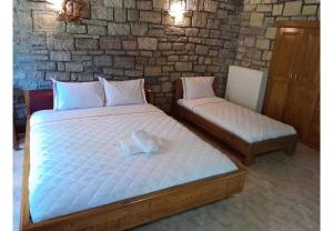 two twin beds in a room with a brick wall at Tsarouxi village 2 in Kardítsa
