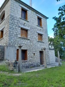 un antiguo edificio de piedra con ventanas en un campo en Tsarouxi village 2 en Kardítsa