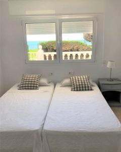 Duas camas num quarto com uma janela em Modern apartment with pool on the beachfront in Marbella by SharingCo em Marbella