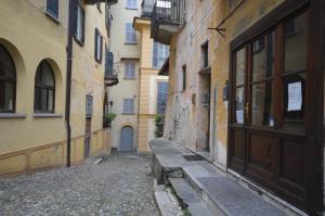 eine Gasse mit einer Holztür und einer Bank neben Gebäuden in der Unterkunft Casa Ginny in Orta San Giulio