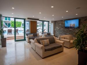 a living room with couches and a tv on a brick wall at Elmi Beach Hotel & Suites in Hersonissos