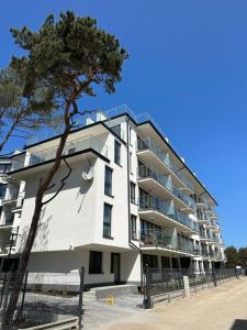 an apartment building with a tree in front of it at Apartament Nadmorski Zakątek Rowy in Rowy