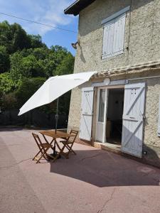 a picnic table with a white umbrella in front of a building at Gîte de l'Eau Vive in Saint-Martin-dʼUriage