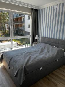 a bedroom with a large bed and a large window at Apartament Nadmorski Zakątek Rowy in Rowy