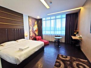 een hotelkamer met een groot bed en een stoel bij Zenz Hotel in Kulai