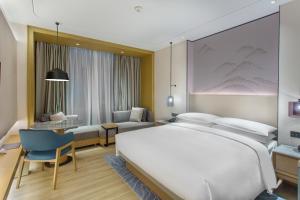 a hotel room with a large bed and a desk at Courtyard by Marriott Foshan Gaoming in Foshan