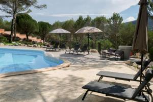 een zwembad met stoelen, tafels en parasols bij Hôtel La Pinède in Saint-Marcellin-lès-Vaison