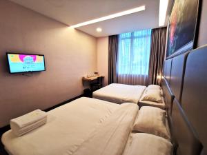 a hotel room with three beds and a flat screen tv at Zenz Hotel in Kulai