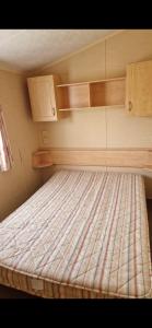 a bed in a small room with wooden cabinets at Skegness Holidays at Haven in Skegness