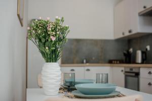 a vase with flowers on a table with plates and glasses at Stylowe apartamenty in Charzykowy