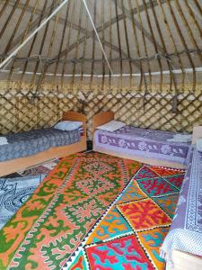 a room with two beds and a rug in a yurt at Guest house and Yurt camp "Ailuu" in Tong