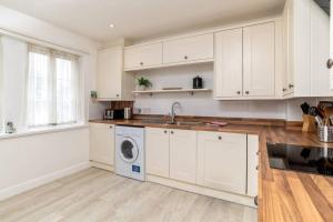 a kitchen with white cabinets and a washing machine at 2 Alexandra Court in St. Andrews