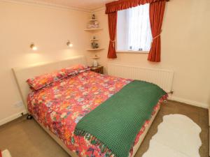 a bedroom with a bed with a green blanket and a window at Middle Cottage in Amble