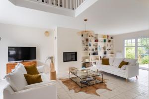 uma sala de estar com dois sofás brancos e uma televisão em La Villa des Rochettes - Charmante maison avec piscine et jardin em Dinard
