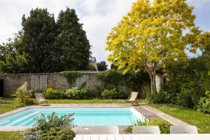 uma piscina num jardim com duas cadeiras e uma árvore em La Villa des Rochettes - Charmante maison avec piscine et jardin em Dinard