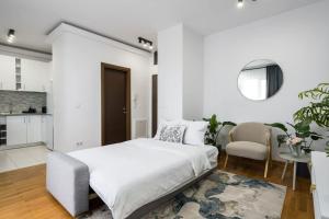 a white bedroom with a bed and a table and chairs at Vivando - Bright 1BR - Amazing Terrace + Parking in Bucharest