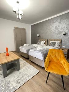 a bedroom with two beds and a table and a chair at Burebista Residence in Deva