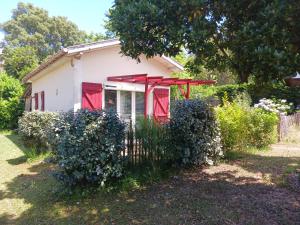 une petite maison blanche avec des fenêtres rouges et une clôture dans l'établissement Maisonnette proche de la plage, à Tarnos