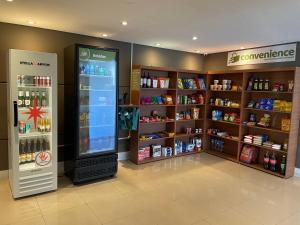 a store with a large refrigerator and shelves of products at Flat Granja Viana - espaço e conforto in Cotia