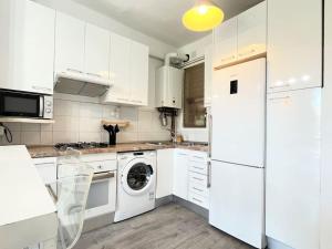 a kitchen with white cabinets and a washer and dryer at Apartamento muy luminoso frente a Parque Joan Miró in Barcelona