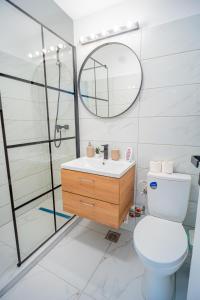 een badkamer met een toilet, een wastafel en een spiegel bij Refreshingly Chic: Newly Renovated 2BR Apartment in Boekarest