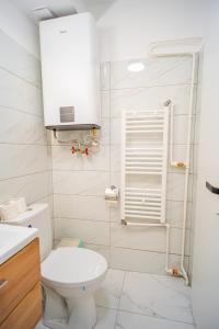 een witte badkamer met een toilet en een wastafel bij Refreshingly Chic: Newly Renovated 2BR Apartment in Boekarest