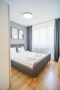 a bed in a bedroom with a large window at Refreshingly Chic: Newly Renovated 2BR Apartment in Bucharest