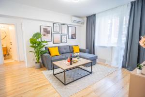 een woonkamer met een blauwe bank en een tafel bij Refreshingly Chic: Newly Renovated 2BR Apartment in Boekarest