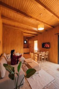 une femme assise sur un canapé dans un salon dans l'établissement SAPANCA KURUÇEŞME TINY HOUSE, à Sapanca