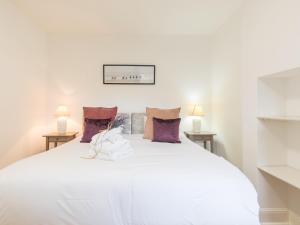 a bedroom with a large white bed with purple pillows at Pass the Keys Chic 1 Bed Flat in Quaint Sunninghill Village in Ascot