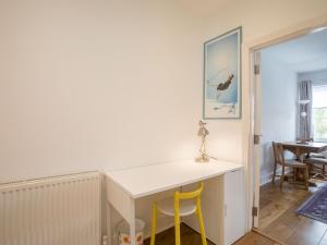 a room with a white desk and two yellow chairs at Pass the Keys Chic 1 Bed Flat in Quaint Sunninghill Village in Ascot