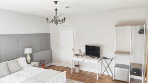 a white living room with a bed and a tv at LONDONDERRYS Bar and Accommodation in Seaham