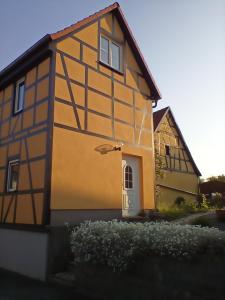 a yellow and black house with a white door at Ferienwohnung Mehlberg in Großlöbichau