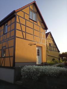 una casa gialla e nera con una porta bianca di Ferienwohnung Mehlberg a Großlöbichau
