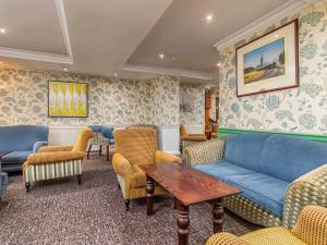 a living room with a blue couch and chairs at Mercure Salisbury White Hart Hotel in Salisbury