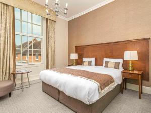 Mercure Salisbury White Hart Hotel في ساليزبري: غرفة نوم بسرير كبير ونافذة كبيرة
