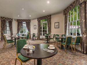 a restaurant with tables and chairs and windows at Mercure Salisbury White Hart Hotel in Salisbury