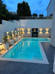 een zwembad in een achtertuin met verlichting bij Apartments Imperium in Trogir