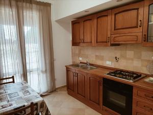 uma cozinha com armários de madeira, um lavatório e uma mesa em Casa Emilia - Appartamento per vacanze - Foligno em Foligno