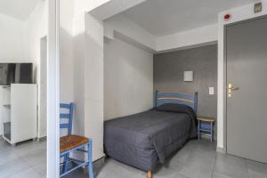 a small bedroom with a bed and two chairs at Hotel Les Palmiers En Camargue in Saintes-Maries-de-la-Mer