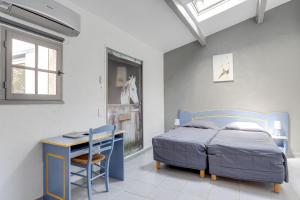 a bedroom with a bed and a desk and a table at Hotel Les Palmiers En Camargue in Saintes-Maries-de-la-Mer