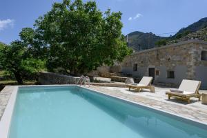 a swimming pool with two chairs and a house at Nomas Home Imbros with Private Pool in Hora Sfakion