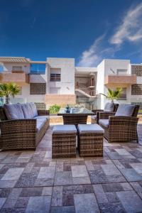 une terrasse avec des chaises et des tables en osier en face d'un bâtiment dans l'établissement Aladdin - Lunja - Luxe - piscines - 6 Px, à Agadir nʼ Aït Sa