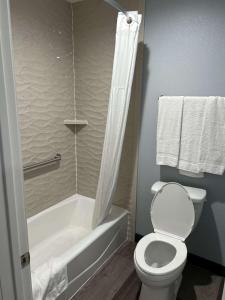 a bathroom with a toilet and a bathtub with a shower curtain at SureStay Hotel by Best Western Buena Park Anaheim in Buena Park